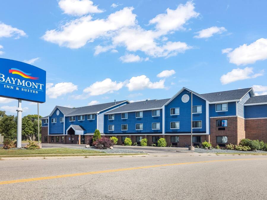 Edificio del Baymont Inn & Suites con fachada azul, numerosas ventanas y cielo despejado.