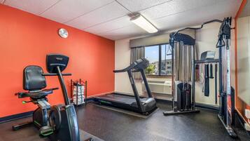 A gym with a treadmill, elliptical, and weight machine.