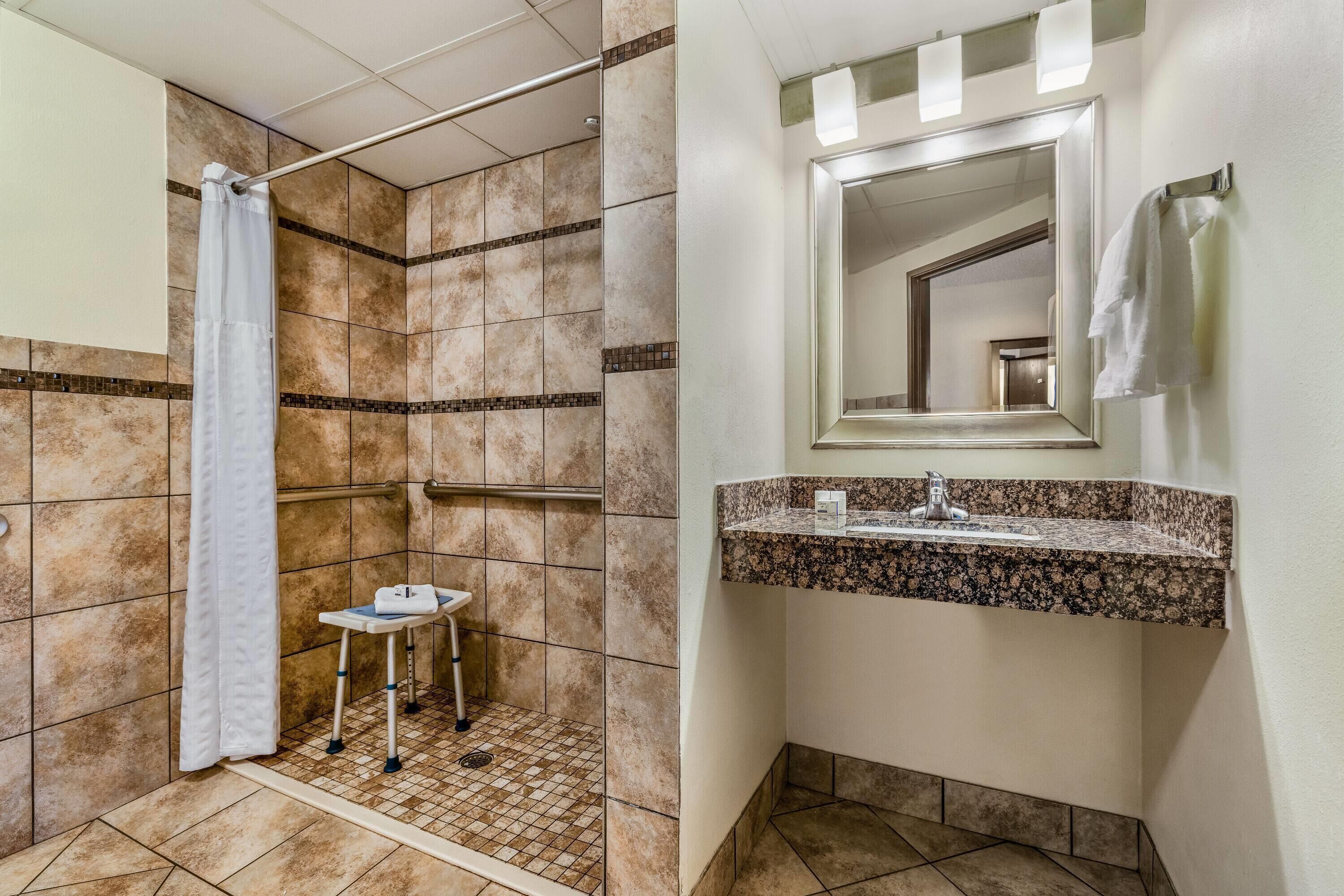 Ein Badezimmer mit Dusche, Waschbecken und Spiegel.