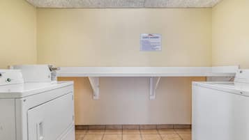 A laundry area with a sign indicating guest laundry services, including operating hours and usage guidelines.