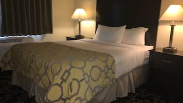 Ein Hotelzimmer mit einem großen Bett, zwei Nachttischlampen, einem dunklen Kopfteil und einer gemusterten Bettdecke.