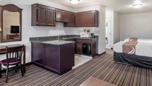 A hotel room with a kitchenette, a bed, a desk with a chair, and a mirror. - Quality Inn Central Roseburg (Roseburg)