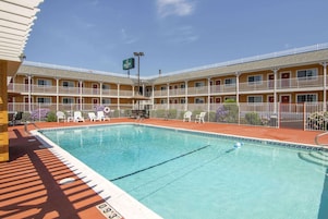 Um motel com piscina, várias varandas e área de estar ao ar livre.
