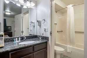 Bathroom features a granite countertop sink, mirror, hair dryers, toilet, and shower.