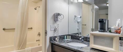 A bathroom with a shower, toilet, sink, and a mirror with lights.