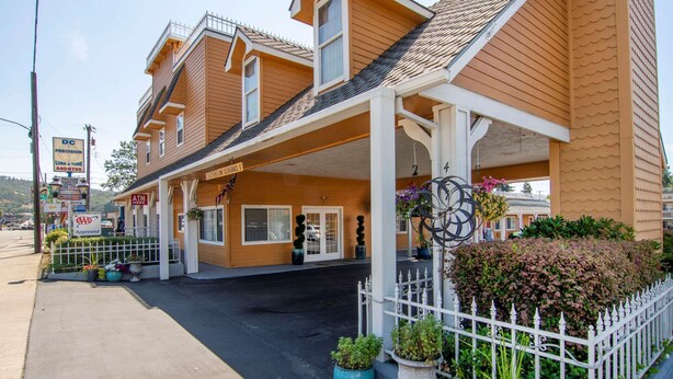 A motel with a covered parking area, a fenced garden, and a sign for a nearby ATM. - Quality Inn Central Roseburg (Roseburg)