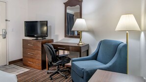 A hotel room with a bed, a desk with a computer, a chair, a television, and a lamp. - Quality Inn Central Roseburg (Roseburg)