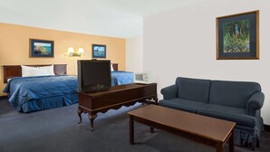 A hotel room with a bed, a sofa, a TV, a small table, and two wall-mounted lamps.