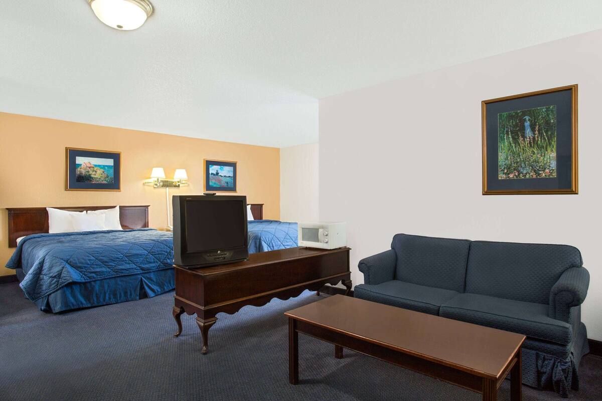 Een hotelkamer met een bed, een bank, een televisie, een tafeltje en twee wandlampen.