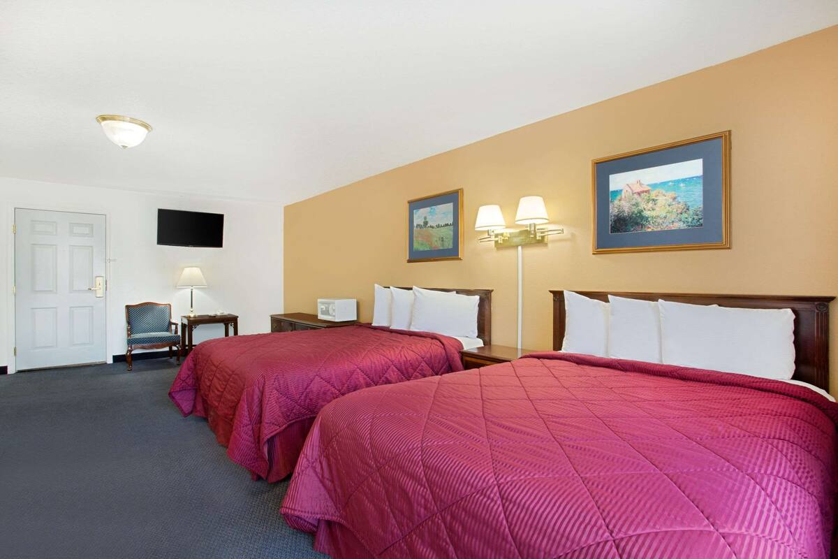 Een hotelkamer met twee bedden, een televisie, een bureau en een stoel.