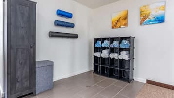Ein Flur mit einem grauen Wandschrank, einer grauen Bank, einem schwarzen Handtuchhalter mit ordentlich gerollten Handtüchern und zwei gerahmten Kunstwerken an der Wand.
