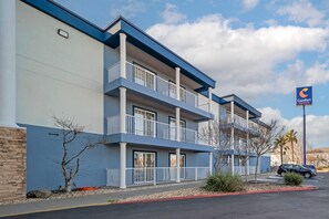 A multi-story hotel with balconies, a parking lot, and a sign for Comfort Suites.