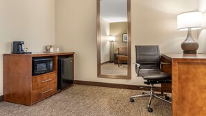 A hotel room with a kitchenette, a large mirror, a desk with a lamp, and a chair. - Comfort Suites Red Bluff near I-5 (Red Bluff)