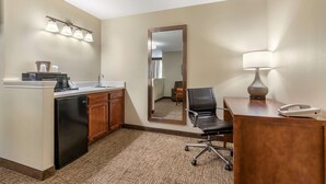 A hotel room with a kitchenette, a mirror, a desk with a lamp, and a chair. - Comfort Suites Red Bluff near I-5 (Red Bluff)