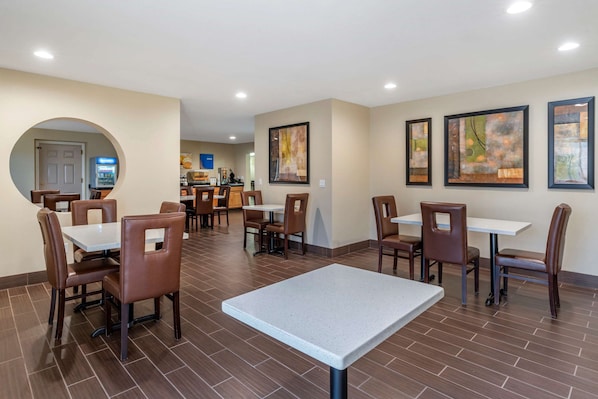 A dining area with tables and chairs, a vending machine, and artwork on the walls. - Comfort Suites Red Bluff near I-5 (Red Bluff)