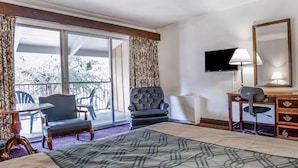 Une chambre d’hôtel comprenant un lit, un bureau avec une chaise, une télévision et un balcon avec des chaises.