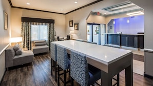 A modern hotel room with a large dining table, a sofa, and a kitchen area. - Best Western Mayport Inn & Suites (Atlantic Beach)
