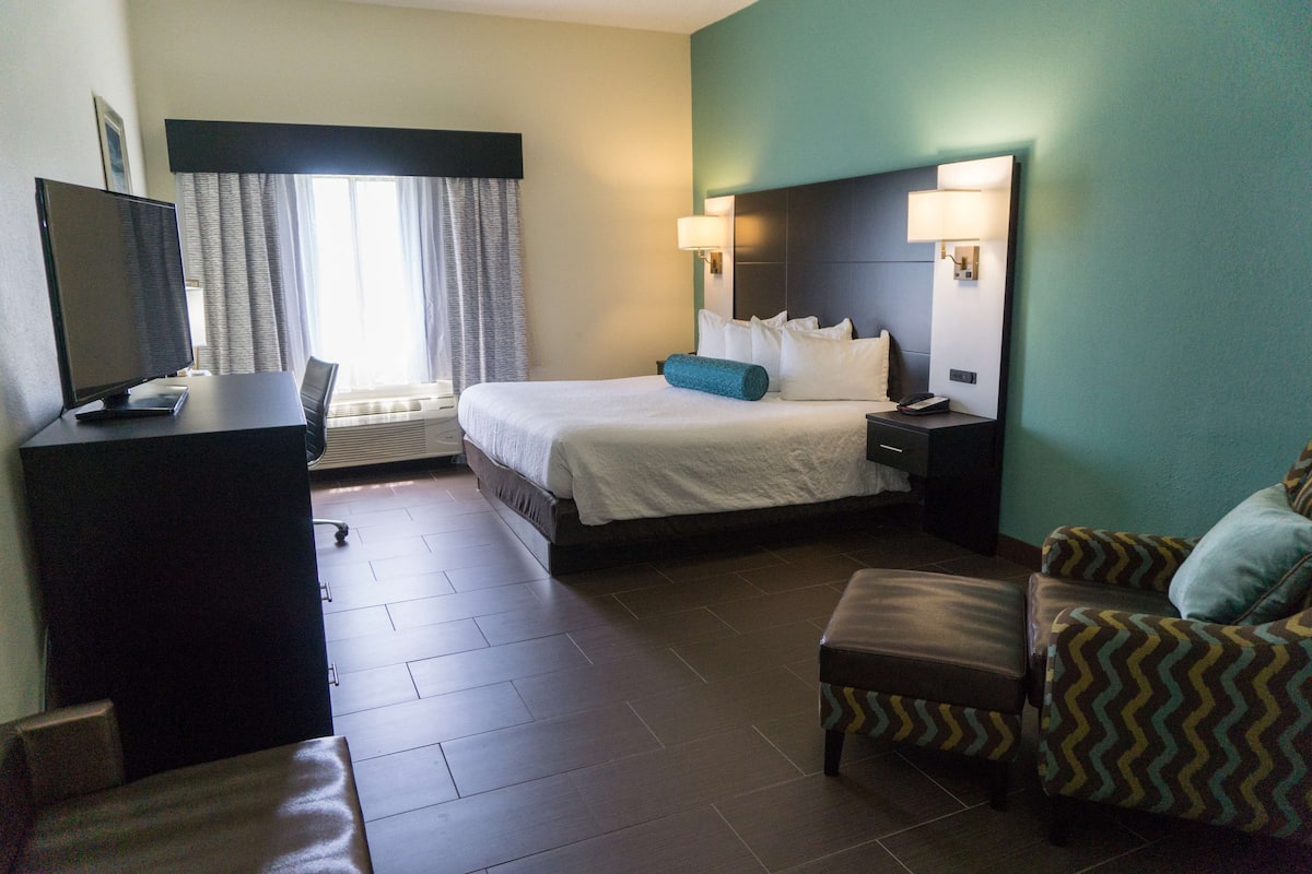 Una habitación de hotel con una cama, un escritorio con una computadora, una silla y un sofá.