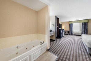 A hotel room with a large bathtub, a bed, a desk with a chair, and a window with curtains. - Best Western Borger Inn (Borger)