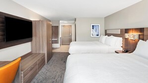 Une chambre d’hôtel avec deux lits, une télévision, un bureau et une chaise.
