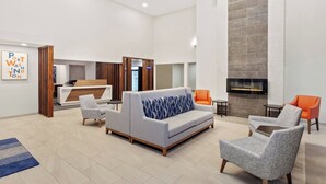 Un hall d’entrée moderne avec un canapé, des fauteuils, un comptoir d’accueil et une cheminée.