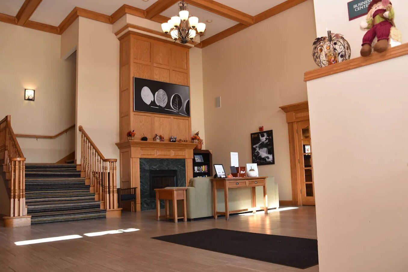 A hotel lobby with a staircase, a fireplace, a reception desk, and artwork on the walls.