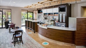 A modern restaurant with a wooden counter, seating area, and large windows. - Courtyard by Marriott Key West Waterfront (Key West)