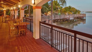 A covered outdoor area with wooden tables and chairs, a view of the water, and a wooden deck with railings. - Courtyard by Marriott Key West Waterfront (Key West)