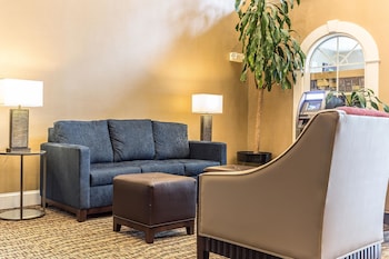 A swimming pool with lounge chairs and umbrellas, surrounded by a building with a gated entrance. at Comfort Suites Myrtle Beach Central