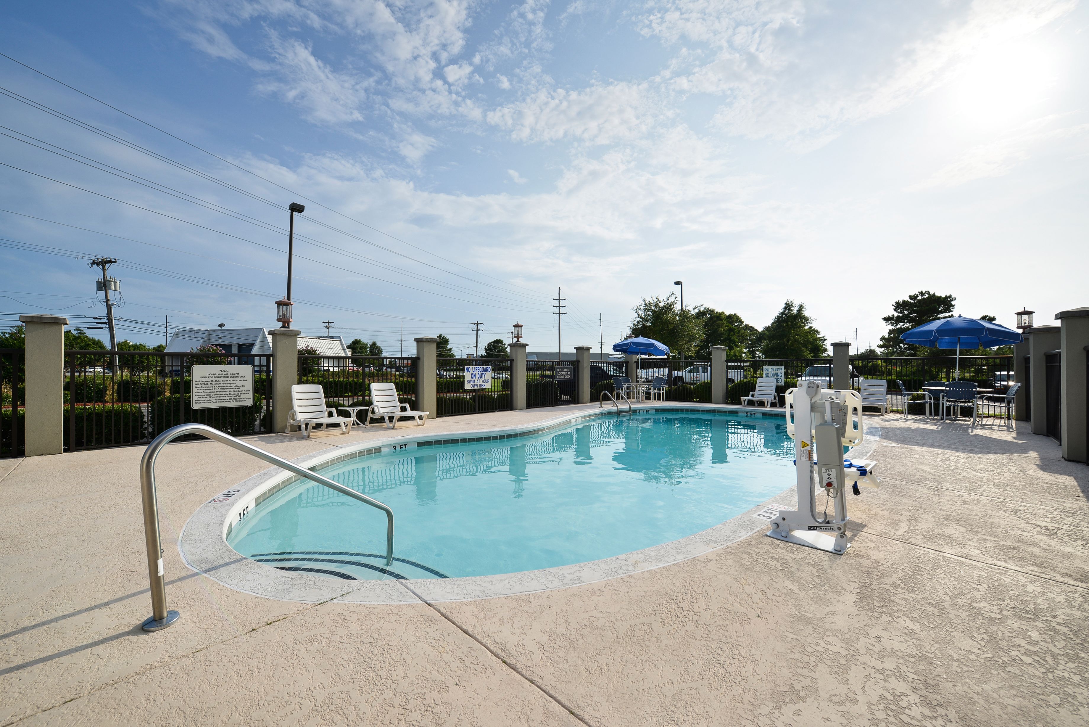 Piscina com posto de salva-vidas, cadeiras de descanso e guarda-sóis.