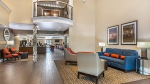 A spacious lobby with a curved staircase, seating areas, and framed artwork on the walls. - Comfort Suites Myrtle Beach Central (Myrtle Beach)