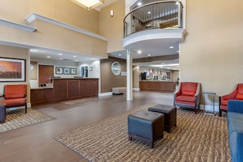 A spacious lobby with a curved staircase, seating areas, and framed artwork on the walls. at Comfort Suites Myrtle Beach Central