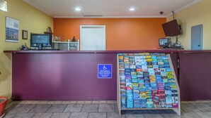 Un área de recepción con mostrador morado, una puerta blanca y una exhibición de revistas.