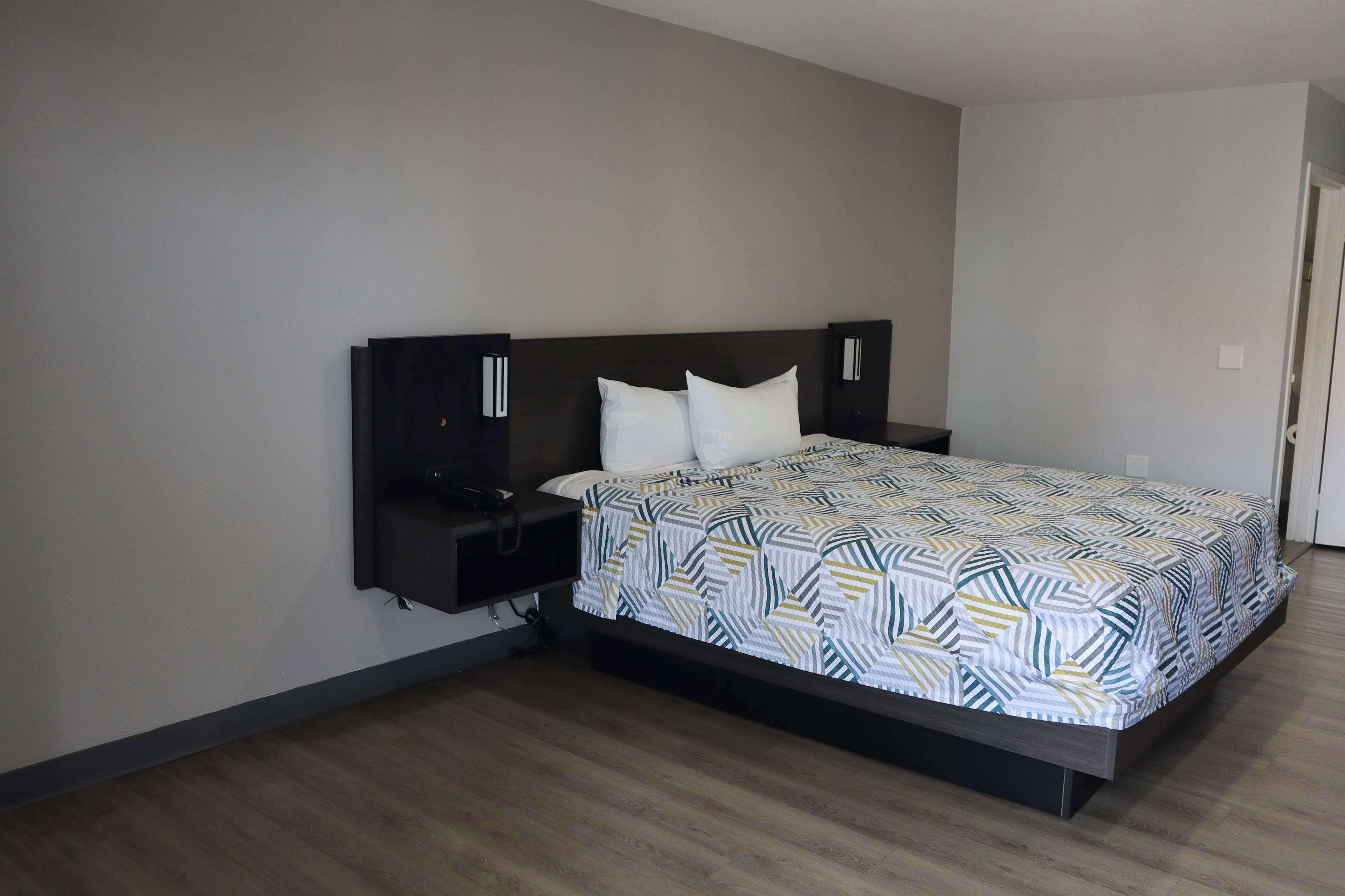 A bedroom with a bed, nightstands, and a wall-mounted TV.