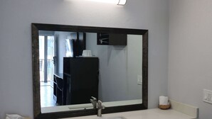 Un baño con un espejo grande, un lavamanos y un dispensador de toallas.