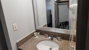 A bathroom with a granite countertop, a white sink, a mirror, and a hairdryer.