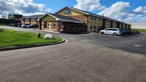 A hotel with a brick facade, a covered entrance, and a parking lot.
