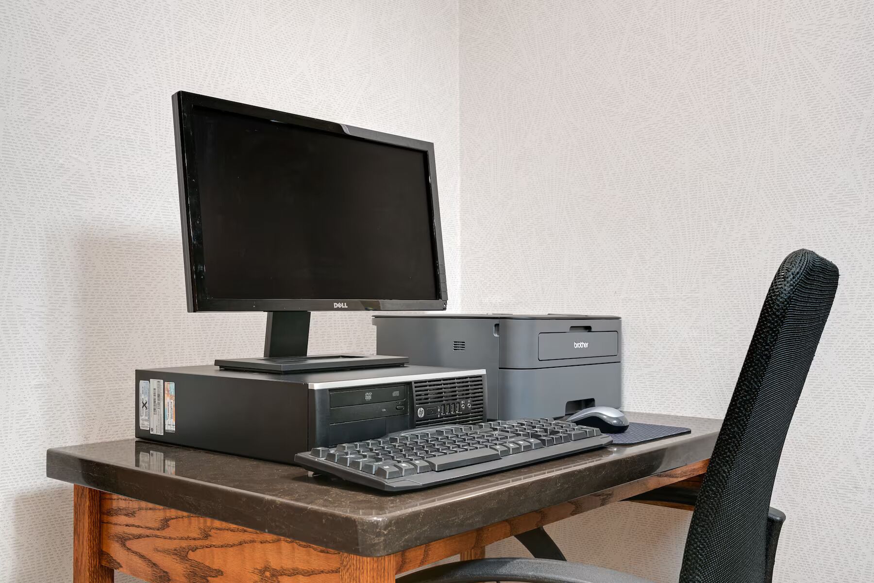 Un escritorio con monitor, teclado e impresora.