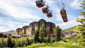A hotel with multiple floors, a golf course, and a ski lift in the background. - Grand Summit Hotel - Canyons Village, a RockResort (Park City)