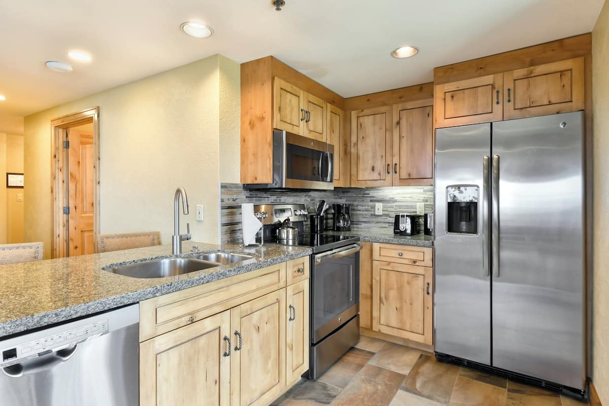 Una cucina moderna con piani in granito, elettrodomestici in acciaio inossidabile, pensili in legno e forno a microonde integrato.