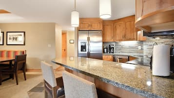 Eine moderne Küche mit Granit-Arbeitsplatten, Edelstahlgeräten, Holzschränken und Pendelleuchten.