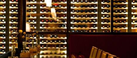A bar with a long counter and multiple wine racks in the background.