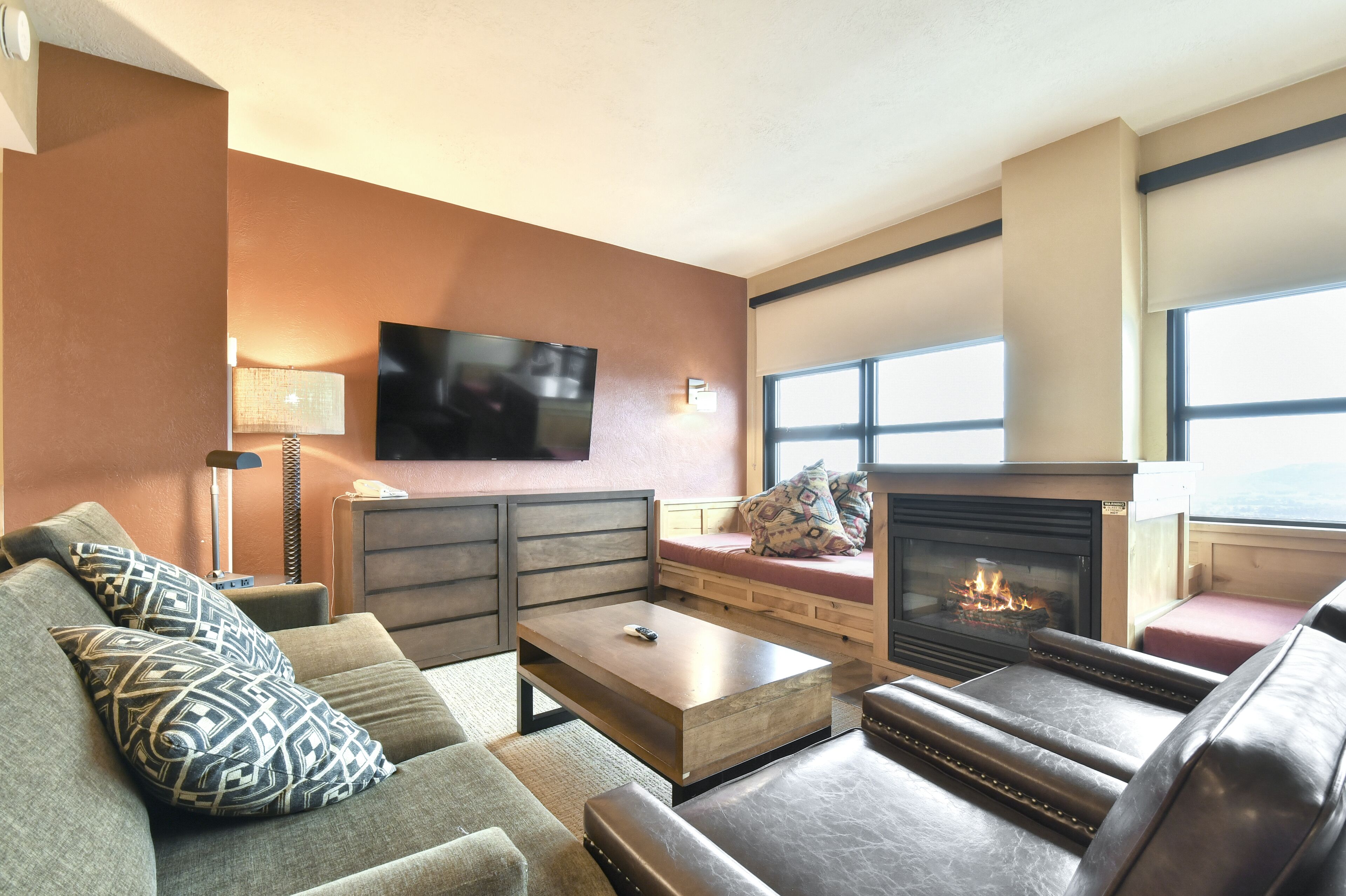 A living room with a fireplace, a sofa, a coffee table, and a television.