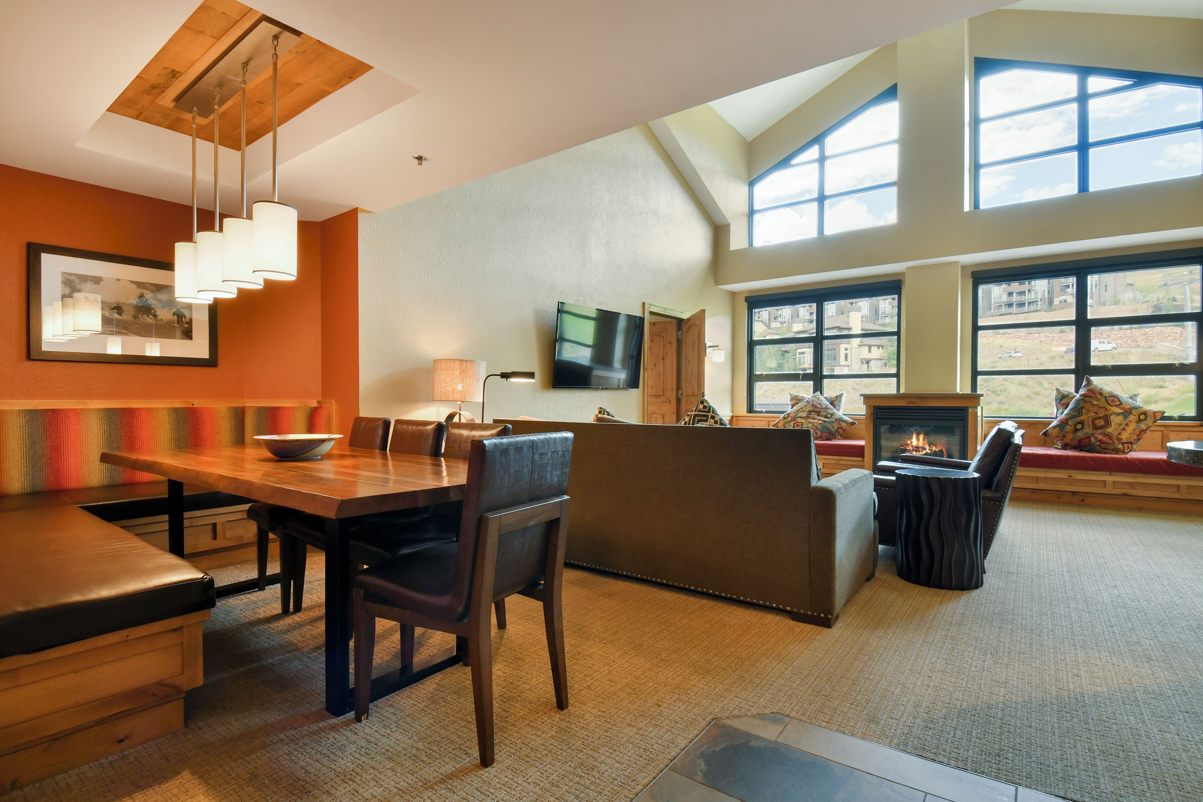 A modern living room with a dining area, large windows, and a fireplace.