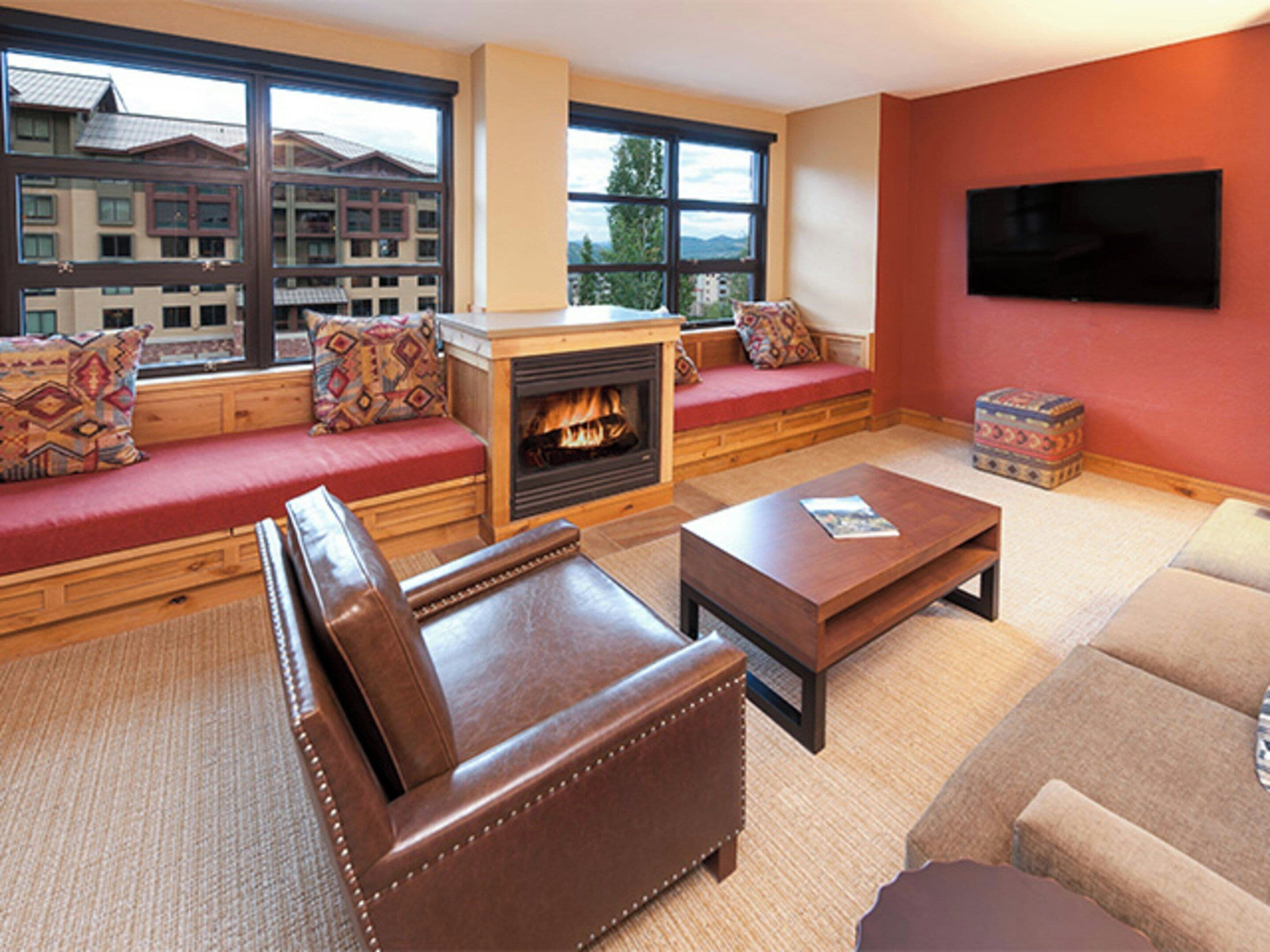 A living room with a fireplace, seating area, and a television.
