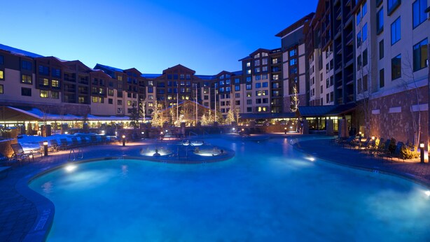 A hotel with a large indoor pool, multiple balconies, and a well-lit courtyard. - Grand Summit Hotel - Canyons Village, a RockResort (Park City)