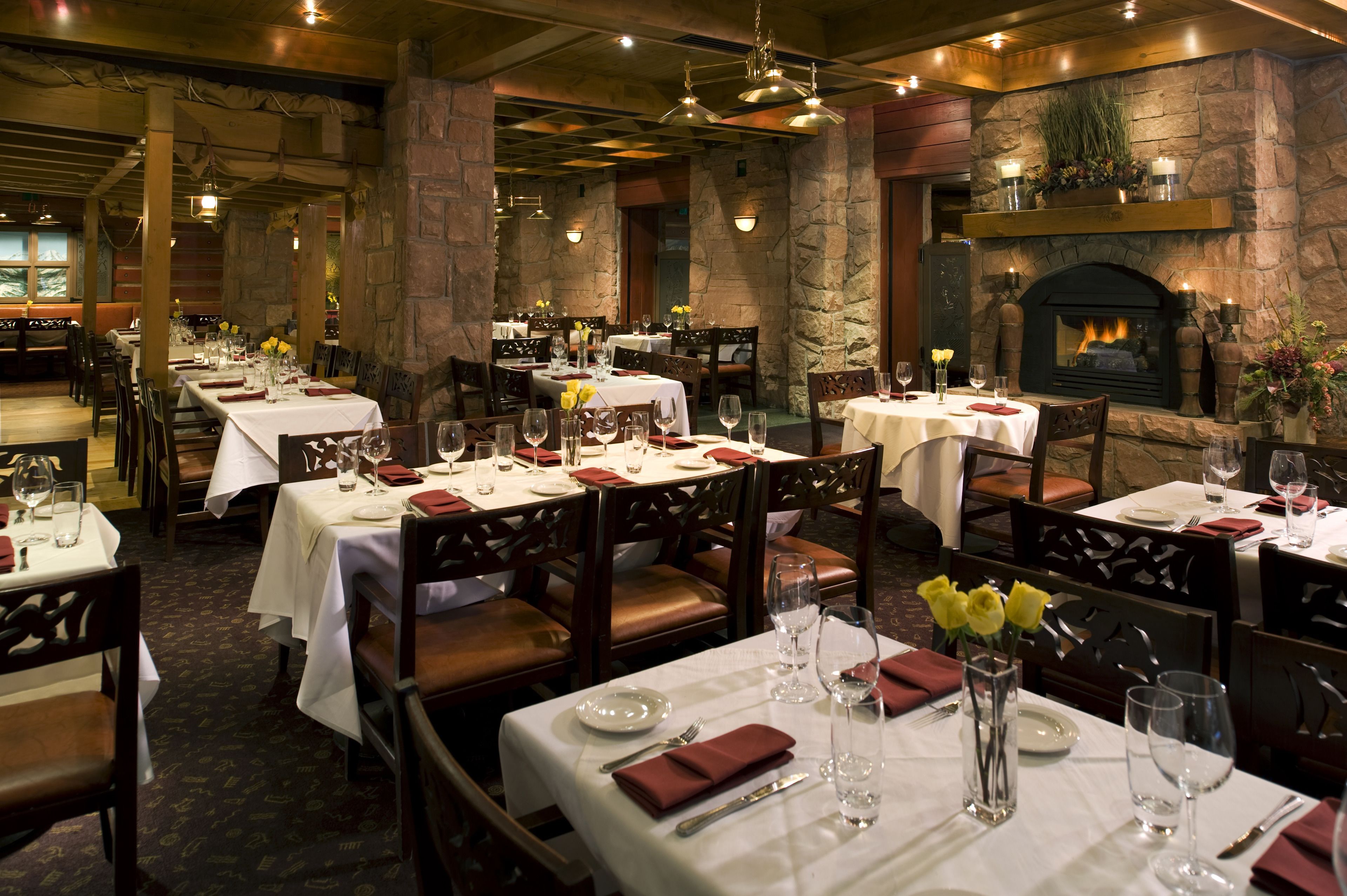 Un restaurant doté de nombreuses tables, avec des murs en pierre et une cheminée.