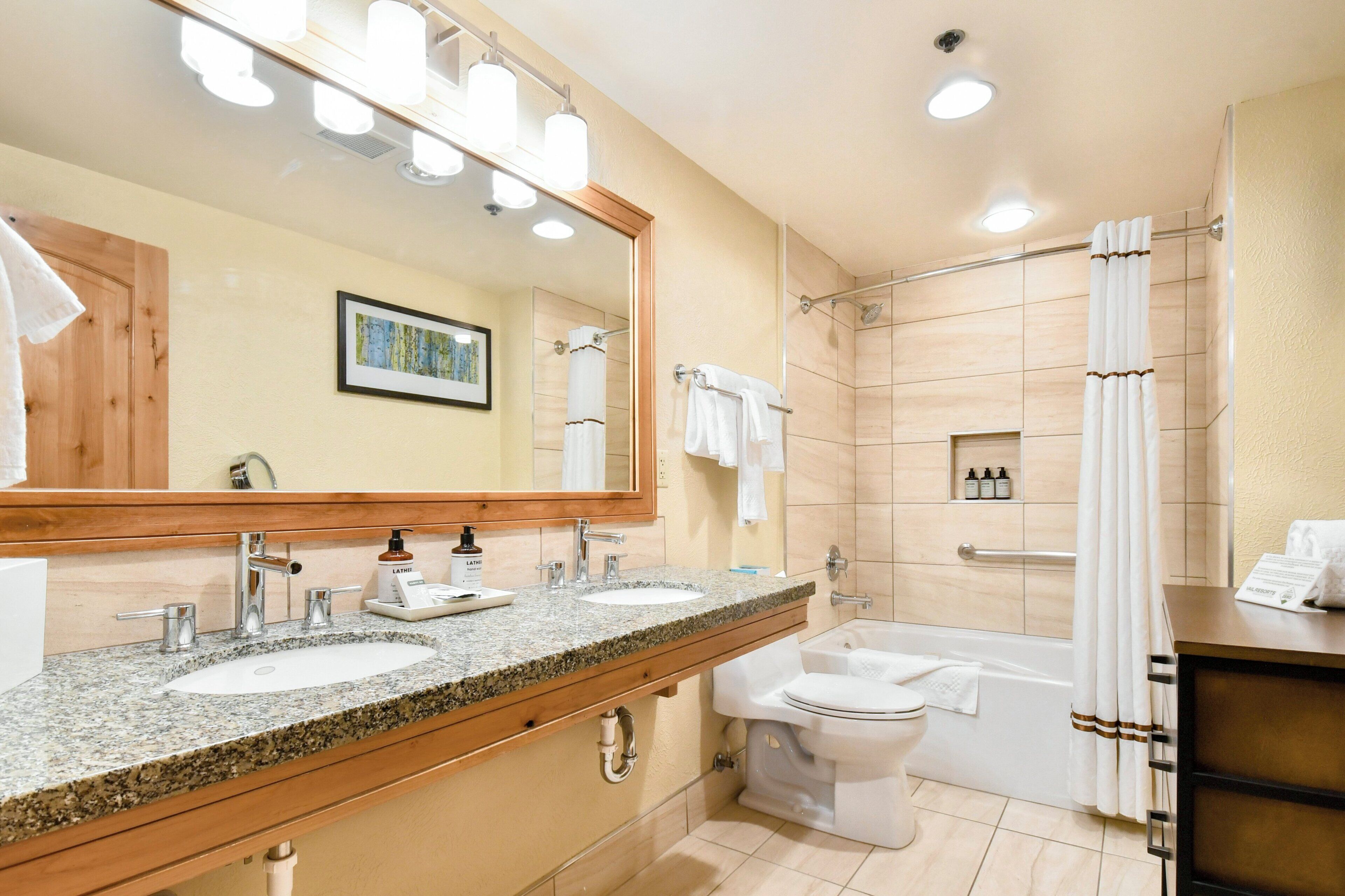 Un bagno moderno con due lavandini, uno specchio grande, una doccia e un water.