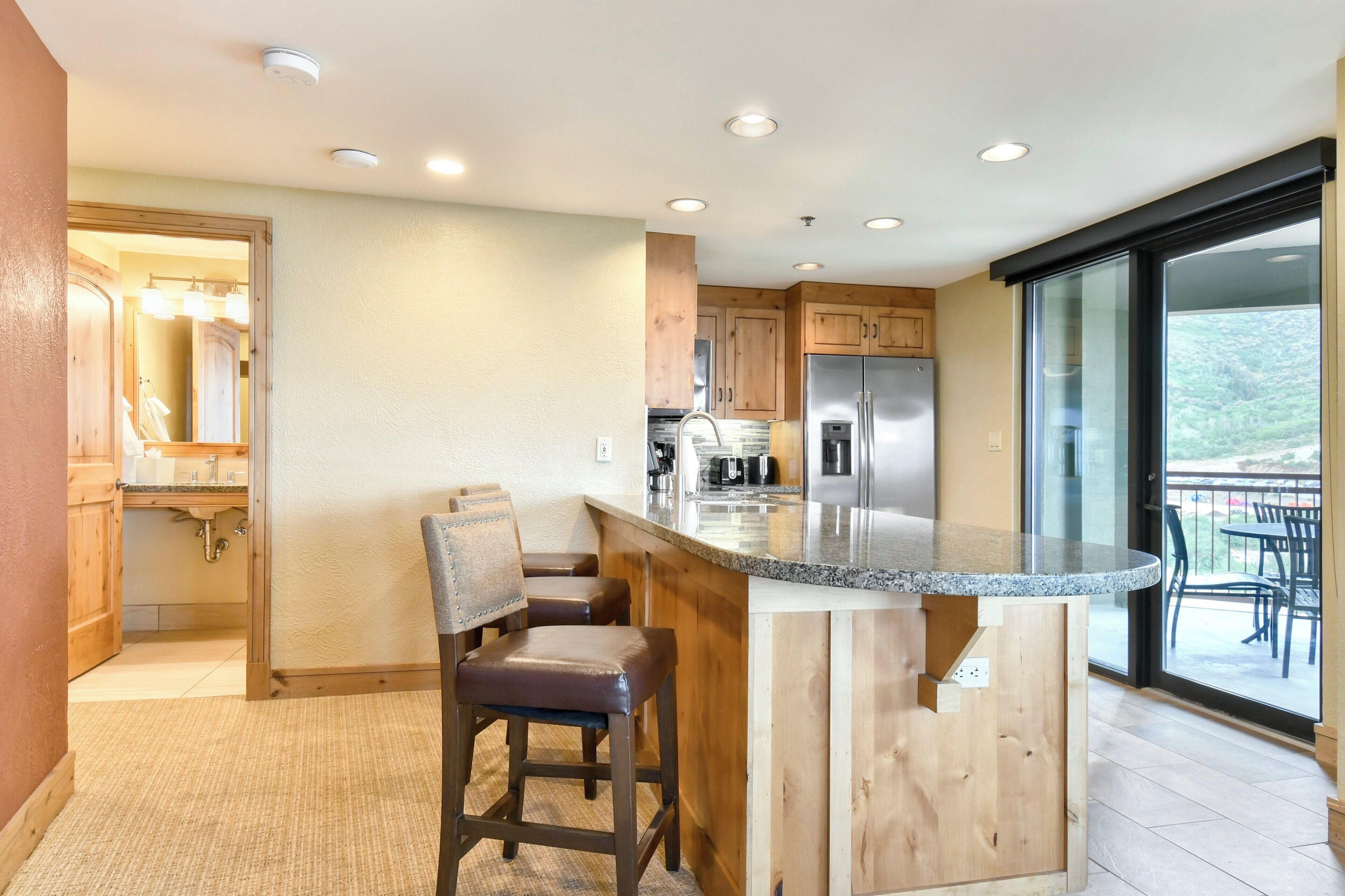 A kitchen with wooden cabinets, a granite countertop, and a built-in island with seating.