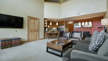 Amplia sala de estar con un televisor de pantalla plana grande, un sofá, una mesa de centro y una chimenea.